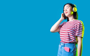 Müzik kulaklıkları dinleyen Asyalı genç bir kadın gözleri kapalı dans ediyor. Kesilmiş telif alanı afişi.