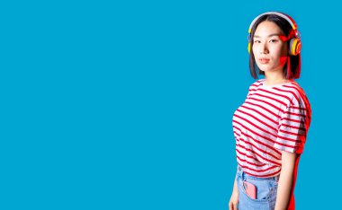 Genç Asyalı kadın arka planı izole etti. Müzik kulaklıklarını ciddi şekilde dinledi. Reklam afişi.