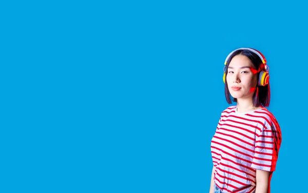 ポートレート若いアジアの女性の隔離されたバックグランドリスニング音楽ワイヤレスヘッドフォン真剣に自信を持って Copyspace Banner — ストック写真
