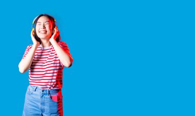 Genç Asyalı kadın arka planda izole edilmiş müzik dinliyor kablosuz kulaklıklar gülüyor - kesilmiş afişler