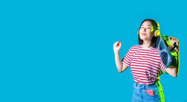Genç Asyalı kadın, müzik kutusuyla müzik dinlerken izole edilmiş. Müzik dinliyor, dans ediyor, gülümsüyor, reklam yapıyor.