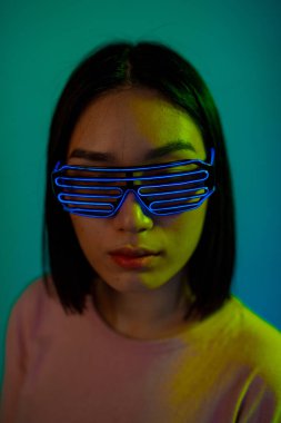 Mavi arka planda fütüristik meta-kurgu gözlük takan genç bir kadın izole edilmiş.