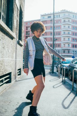 Genç melez kıvırcık saçlı kadın dışarıda dans ediyor özgürce hayatın tadını çıkarıyor.