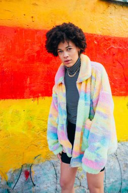 Genç, melez kıvırcık saçlı, şık, kendine güvenen ve ciddi bir kadın.