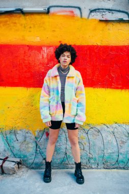 Genç, melez kıvırcık saçlı, şık, kendine güvenen ve ciddi bir kadın.