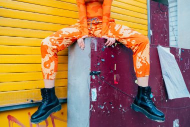 Dışarıda poz veren tanınmamış bir kadın şık kıyafetler ve siyah çizmeler giyiyor.