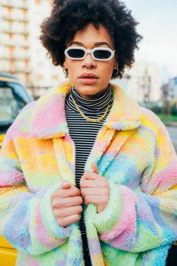 Kendine güvenen genç siyahi kadın açık havada bağımsız poz veriyor. Kararlı ve soğukkanlı.