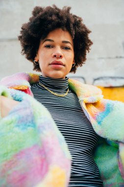 Kendine güvenen genç siyahi kadın açık havada bağımsız poz veriyor. Kararlı ve soğukkanlı.