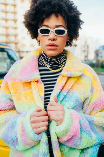 Kendine güvenen genç siyahi kadın açık havada bağımsız poz veriyor. Kararlı ve soğukkanlı.