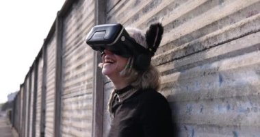 Ağır çekim 4k ultra hd makyajsız genç bir kadın dışarıda poz veriyor metaverse artırılmış gerçekliğin tadını çıkarıyor 5D kablosuz gözlüklü 3D kulaklıkla