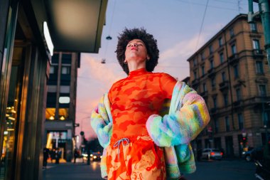 Kentin dışında poz veren gururlu genç zenci kadın. Güçlü ve kendine güvenen eller kalçalarda.