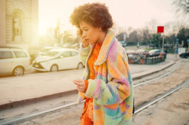 Genç kıvırcık siyah kadın akıllı telefon kullanıyor ya da sesli mesaj kaydediyor.