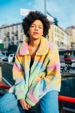 Havalı siyah kadın afro kıvırcık saç pozu veriyor. Pozitif bakıyor.
