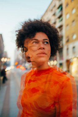 Çifte pozlama genç kıvırcık kadın poz veriyor. Gün batımında rüya gibi ve dalgın bakıyor.