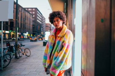 Kendine güvenen genç siyahi kadın açık havada bağımsız poz veriyor. Kararlı ve soğukkanlı.