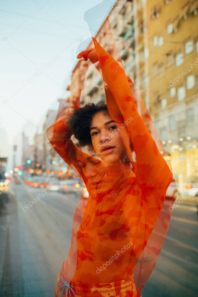 Double exposure young black woman curly hair stretching arms posing outdoors city feeling free