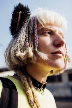 Konformist olmayan genç kadın alternatif değişik pozlar veriyor. Kameraya güçlü ve bağımsız bakıyor.