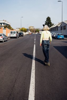 Arkaya bakan, şehir dışında paten yapan genç bir kadın asi ve sportif.