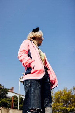 Young nonconformist rebel woman gender fluid posing outdoor looking over pensive