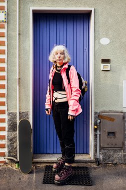 Young rebel gender fluid natural beauty skater woman posing outdoors