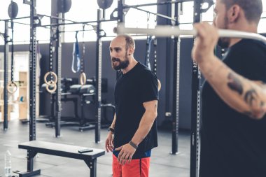 Young athletic man indoors gym taking break training wearing sportswear chatting