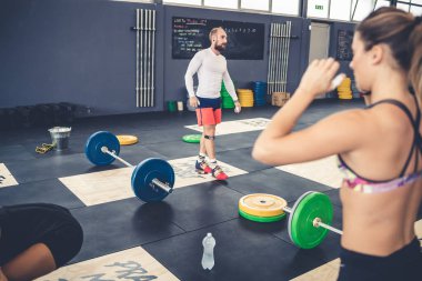 Young athletic man indoors gym training weight lifting together teammates