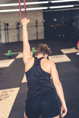 Genç formda atletik kadın spor salonunda esneme hareketleri yapıyor elastik bant kullanarak.