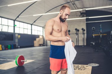 Gömleksiz, kaslı, spor salonundaki sporcu antrenmana hazırlanıyor.