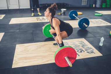 Odaklanmış, sağlıklı genç bir kadın. Spor salonunda ağırlık kaldırıyor. 