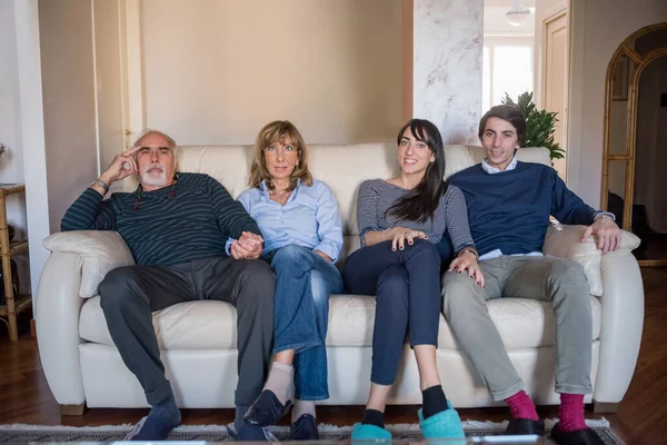 年长的已婚夫妇坐在沙发上 年幼的儿子和女儿面带微笑 — 图库照片