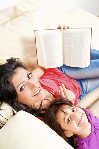 Mutter und Tochter lächeln beim Lesen eines Buches — Stockfoto