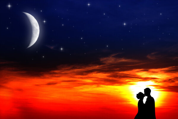 Two young lovers kissing at sunset