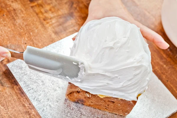 Verspreiding van crème op taart met spatel — Stockfoto