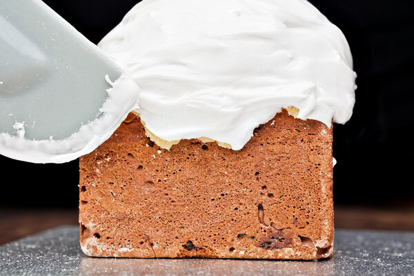 Spreading cream on cake with spatula