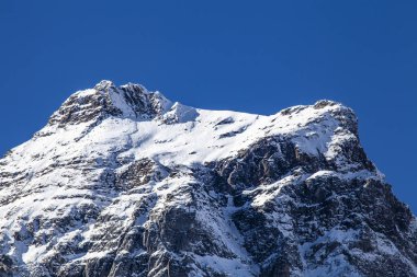 Kışın açık mavi gökyüzüyle Alp karlı zirvesi