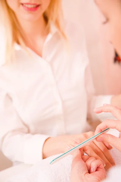 Professional manicurist giving treatment to young woman — Stock Photo, Image