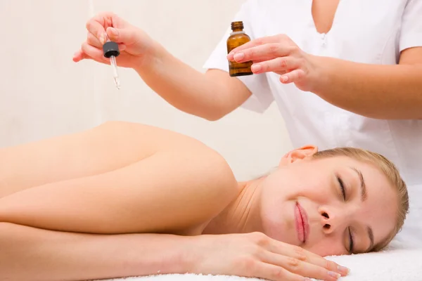 Therapist putting essential oil woman's back — Stock Photo, Image