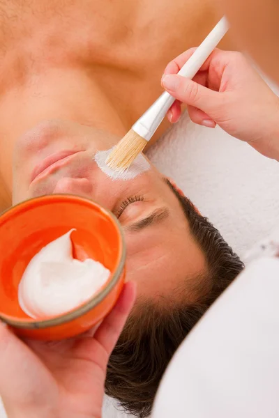 Terapeuta aplicando crema en la cara del hombre — Foto de Stock