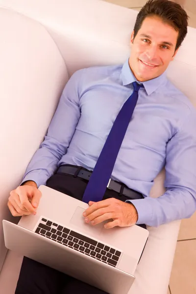 Joven hombre de negocios acostado sofá utilizando el ordenador portátil —  Fotos de Stock