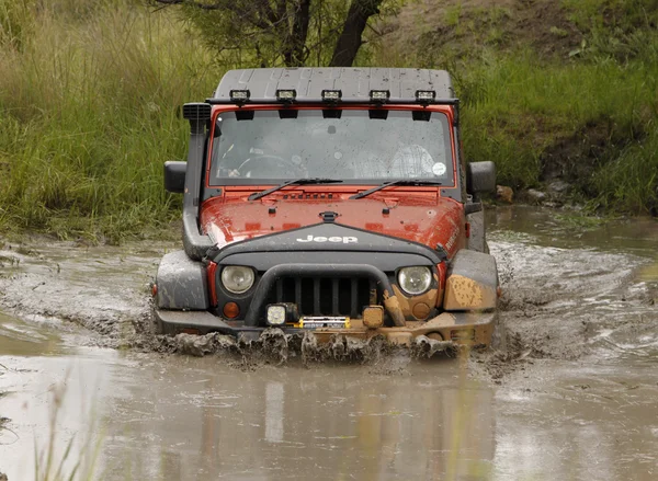 Turuncu jeep rubicon crossing çamurlu su birikintisi ezmek — Stok fotoğraf