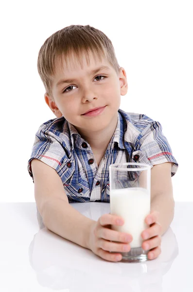 Niño feliz con un vaso de leche apoyado en la mesa — Foto de Stock
