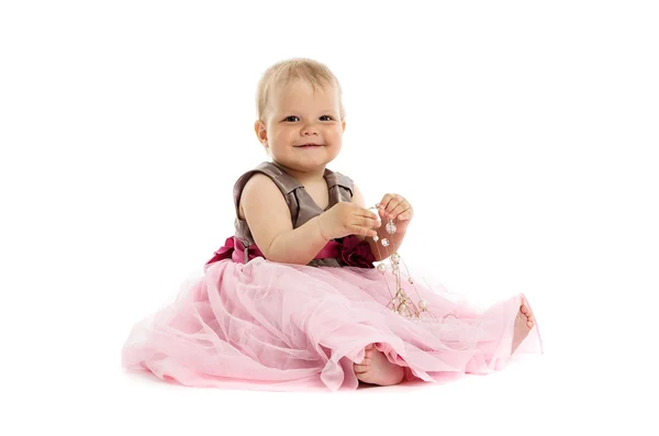Roztomilá malá holčička v růžových šatech sedí na podlaze — Stock fotografie
