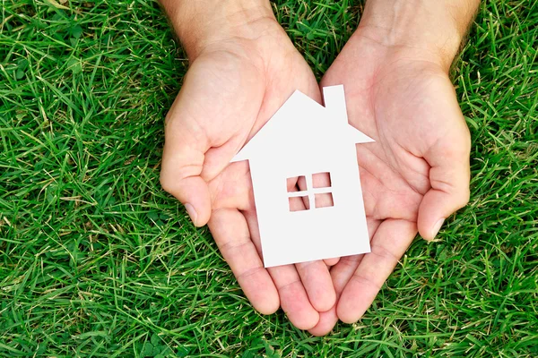 Hand hold house against green field — Stock Photo, Image