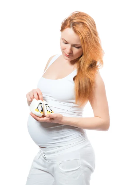 Schwangere hält Hausschuhe für kleine Kinder in der Hand — Stockfoto