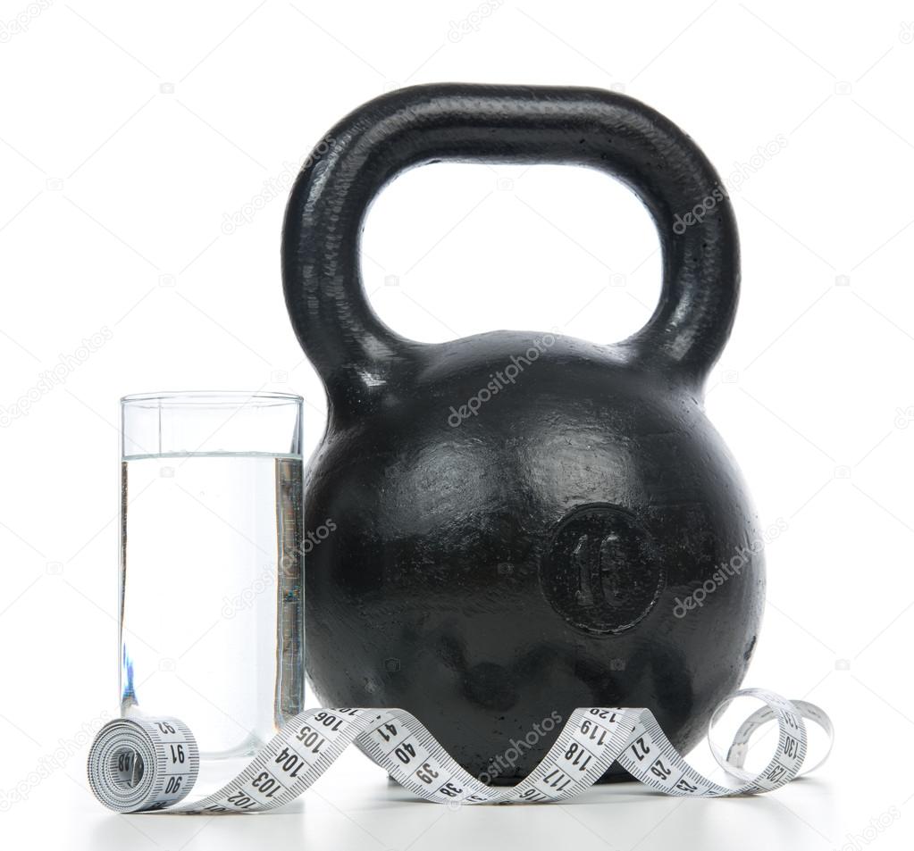 Big black fitness weight with tape measure and glass of drinking