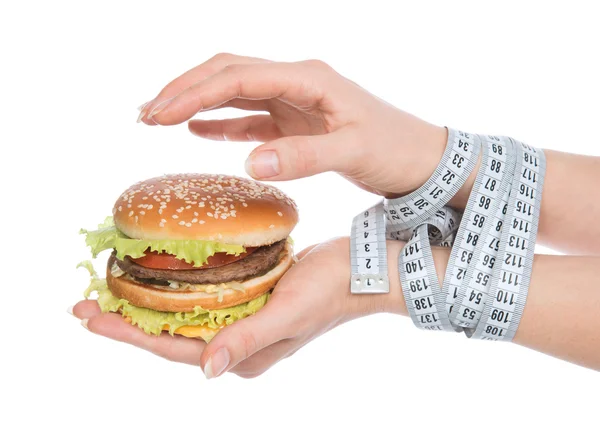 Burger cheeseburger in hands with measure tape — Stock Photo, Image