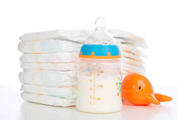 Child stack of diapers and baby feeding bottle with milk — Stock Photo, Image