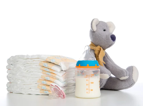 New born child stack of diapers, nipple soother, teddy bear toy — Stock Photo, Image
