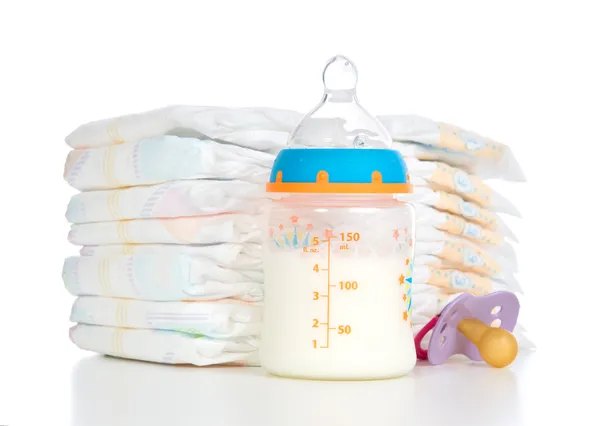 Stack of diapers nipple soother and baby feeding bottle with mil — Stock Photo, Image