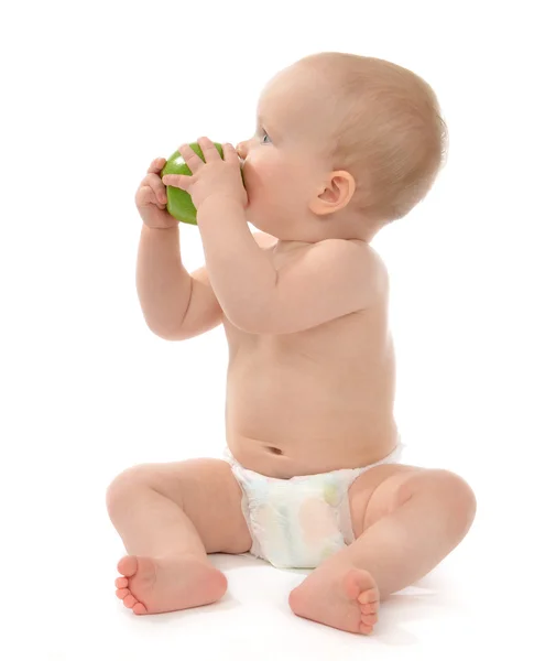 Child baby boy sitting in diaper and eating green apple — Stock Photo, Image